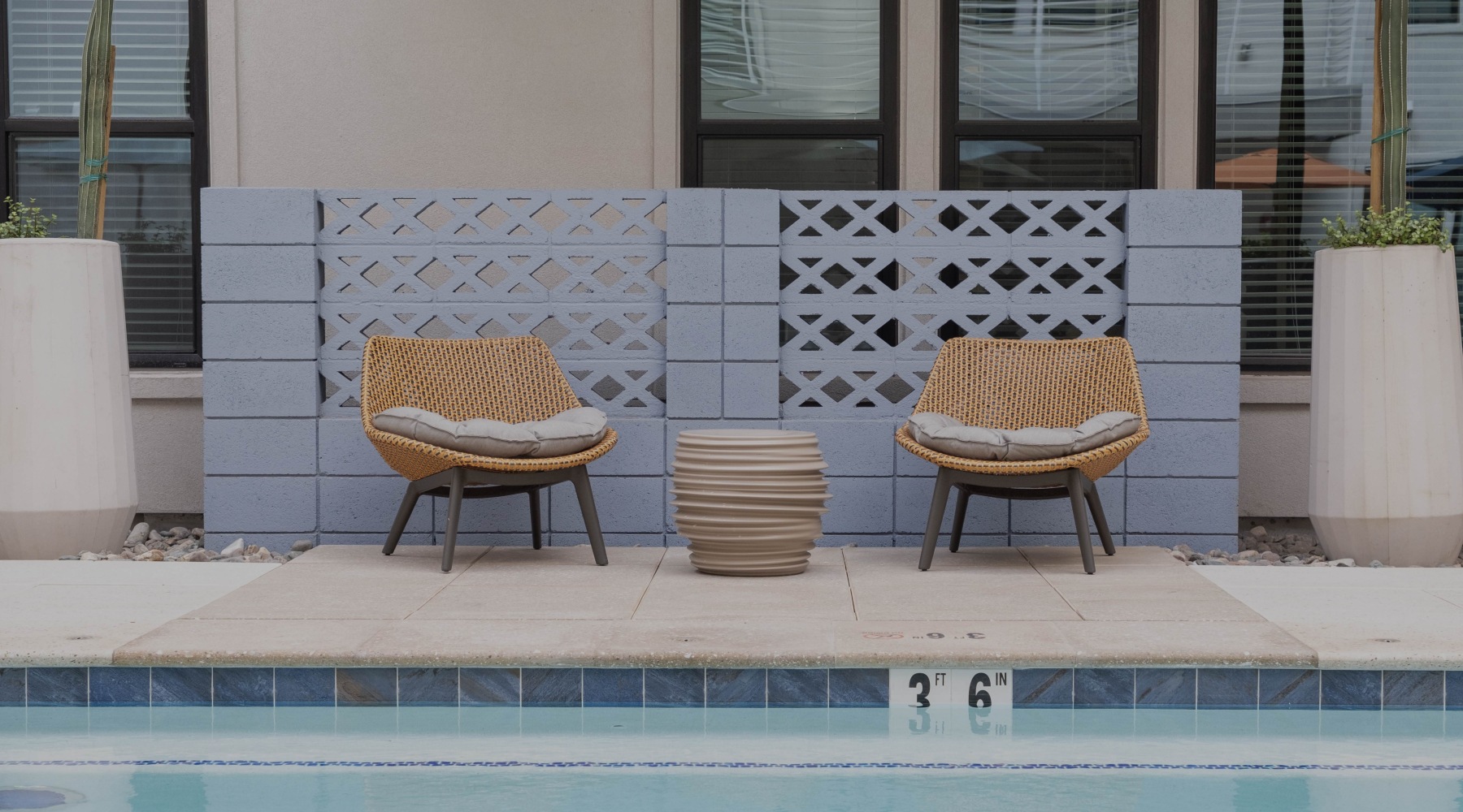 two chairs with a small table in front of the pool
